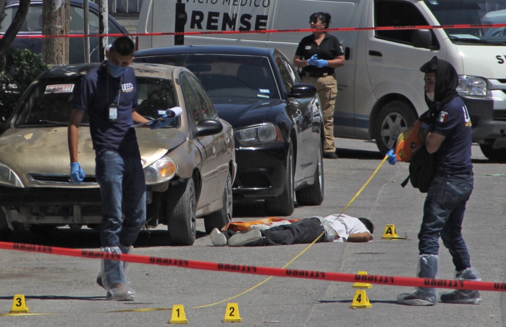 Forensic experts and investigators of the prosecution office work at the crime scene next to a man's corpse in Ciudad Juarez, Mexico, on April 20, 2019.