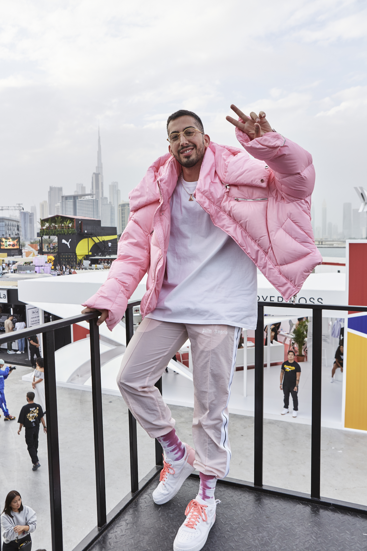 A man stands against the Dubai skyline in a full pink outfit