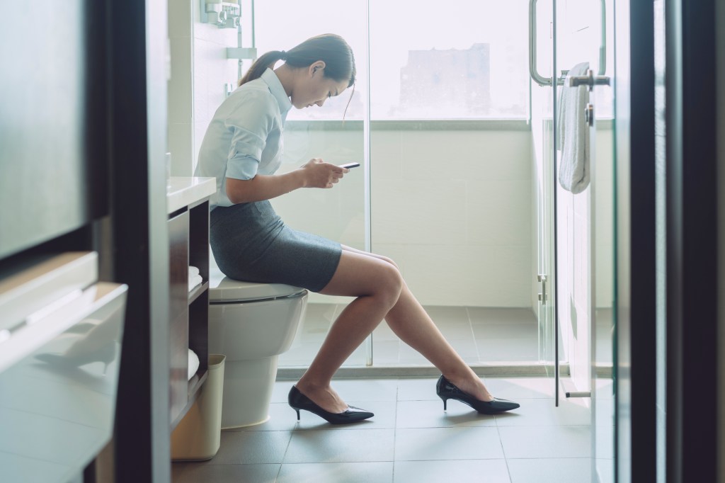 woman texting in bathroom at work