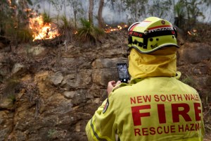 A firefighter uses his phone to take a photo of the fire's edge near Mangrove Mountain, north of Sydney