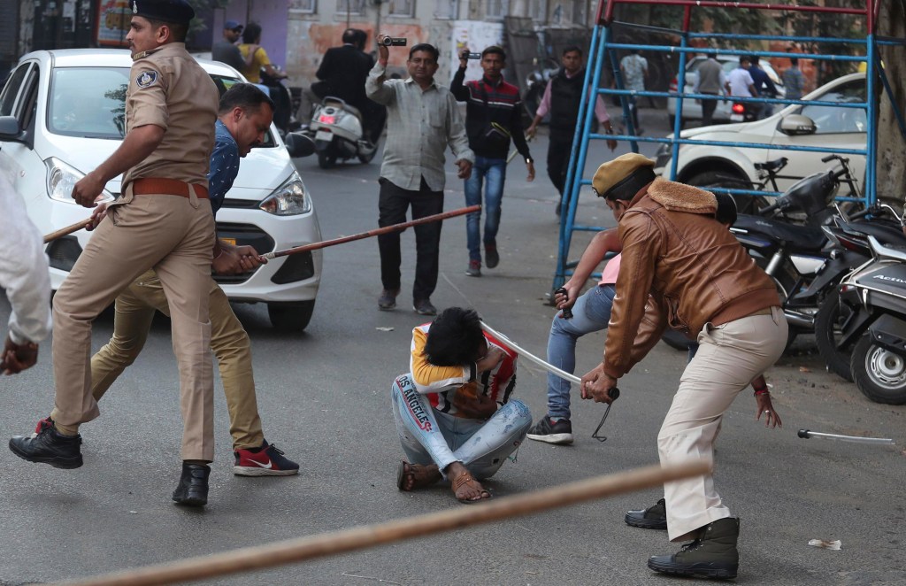 Indian policemen baton charge a man during a protest against a new citizenship law in Ahmadabad, India,