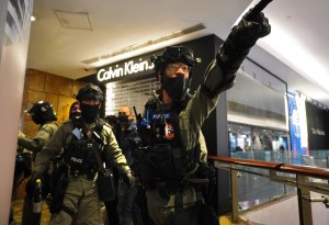 Riot police gesture as they gather at a shopping mall during a demonstration in Hong Kong, Thursday, Dec. 26, 2019.