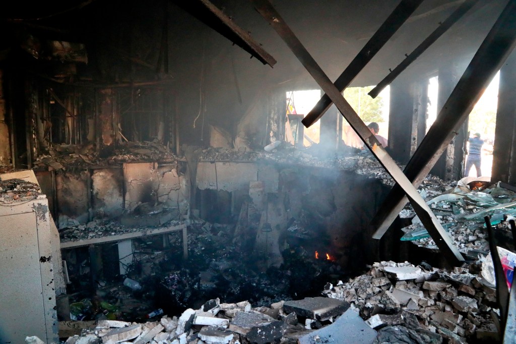 Pro-Iranian militiamen and their supporters are seen through broken windows of a burned checkpoint in front of the U.S. embassy in Baghdad, Iraq, Wednesday, Jan. 1, 2020. (AP Photo/Khalid Mohammed)​ (AP Photo/Khalid Mohammed)​