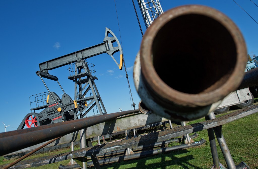 A dark pipe opening next to an oil well.