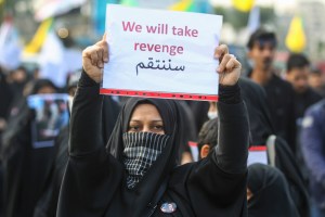 An Iraqi woman holds a placard during the funeral of Iranian military commander Qasem Soleimani, Iraqi paramilitary chief Abu Mahdi al-Muhandis and eight others in Baghdad's district of al-Jadriya, in Baghdad's high-security Green Zone, on January 4, 2020