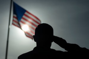 In this photo taken Aug. 26, 2019 and released by the U.S. Air Force, U.S. Air Force Staff Sgt. Devin Boyer, 435th Air Expeditionary Wing photojournalist, salutes the flag during a ceremony signifying the change from tactical to enduring operations at Cam