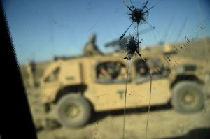 A view of an armored vehicle through glass with bullet holes in it.