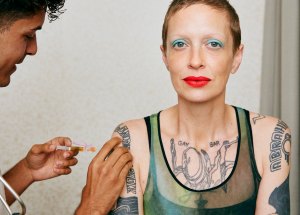 A woman with tattoos receives a vaccine.