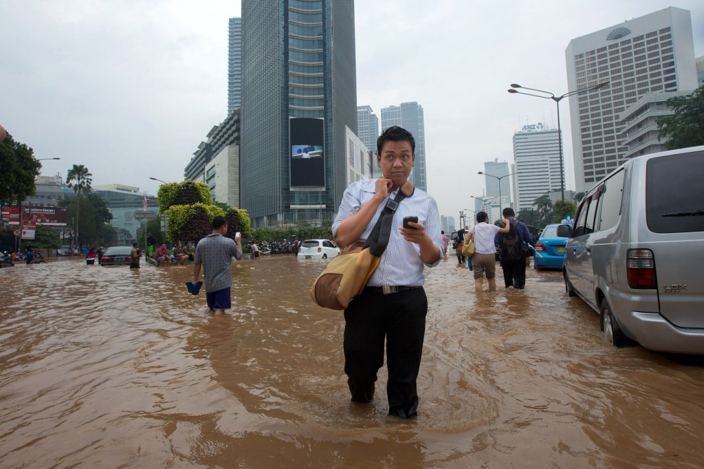 Man walking in flooded Jakarta street.