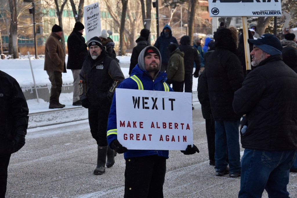 Man holds a Make Alberta Great Again sign.