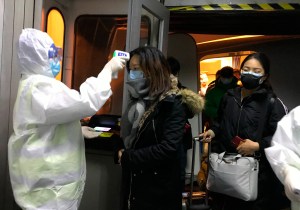 ​Foto: AP Photo / Emily Wang - Operatori sanitari in tute anticontaminazione controllano la temperatura dei passeggeri che arrivano dalla città Wuhan, all'aeroporto di Beijing, Cina, mercoledì 22 gennaio 2020