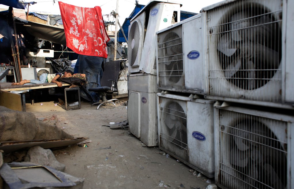 n this Tuesday, May 17, 2016 file photo, an Indian boy of a migrant daily wageworker sleeps in scorching summer temperatures near an air conditioner shop at a marketplace in New Delhi, India.