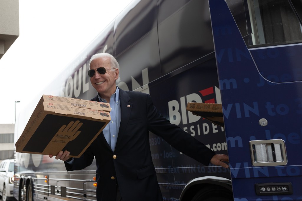 Democratic presidential candidate former Vice President Joe Biden carries a pizza box before speaking at a stop event in Des Moines, Iowa on February 3, 2020.