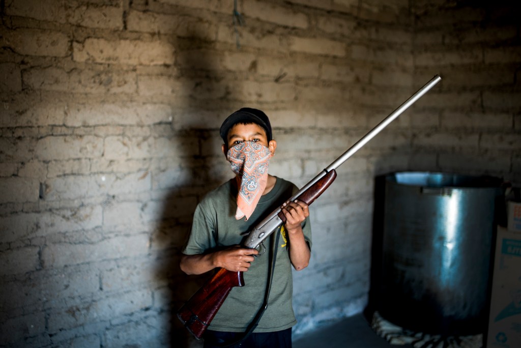 Luis, 13, has become a leader of the junior militia. He rarely leaves the house without his 20-caliber shotgun.