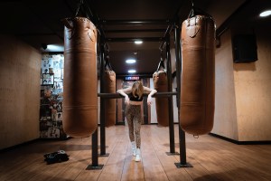 Eine Frau lehnt erschöpft zwischen zwei Boxsäcken