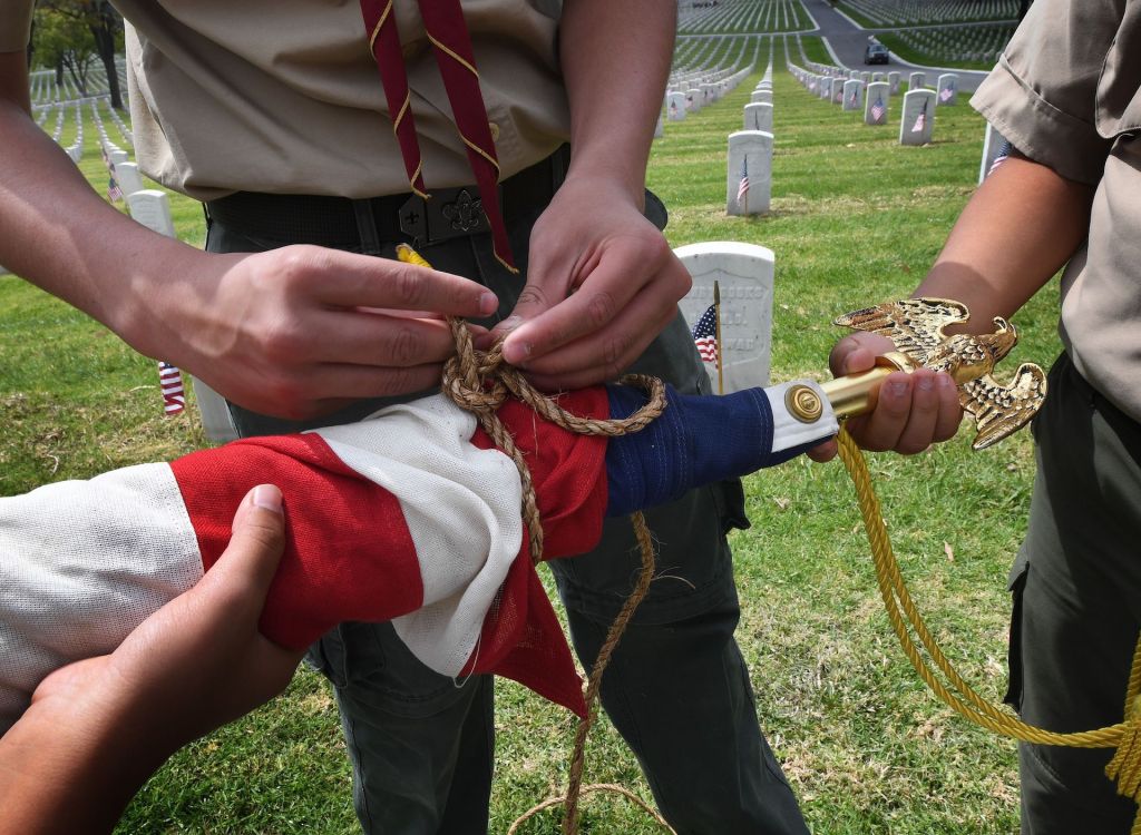 Boy Scouts from the Long Beach troop prepare a US flag besides the graves of war veterans during the annual 'Flag Placement ceremony' to honor the fallen for Memorial Day at the Los Angeles National Cemetery, California on May 25, 2019.