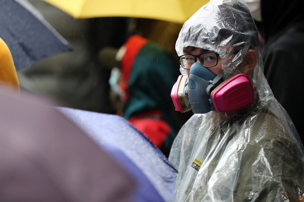 A demonstrator wears a gas mask in the rain during a protest against the use of Chun Yeung Estate as a quarantine center in the Fo Tan area of Hong Kong, China, on Sunday, Feb. 16, 2020