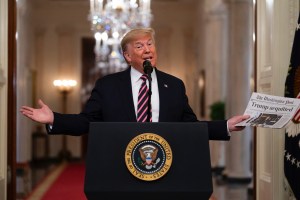 President Donald Trump holds up a newspaper tat reads "Trump acquitted" during during an event celebrating his impeachment acquittal, in the East Room of the White House, Thursday, Feb. 6, 2020, in Washington. (AP Photo/Evan Vucci)