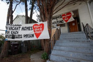 In this Jan. 14, 2020 file photo, signs are posted outside of a house was occupied by the group Moms 4 Housing in Oakland, Calif.