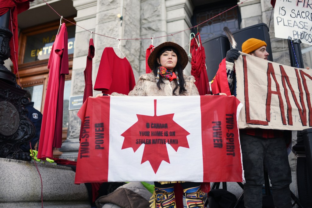 Land defender stands in front of the B.C. Legislature in Victoria.