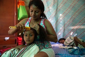 Leibis Garcia combs her daughter's hair in the bedroom that they share as a family. (