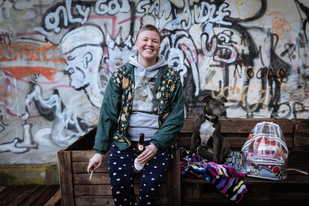 Een dakloze vrouw poseert met haar tas waar maandverband en dergelijke in zitten