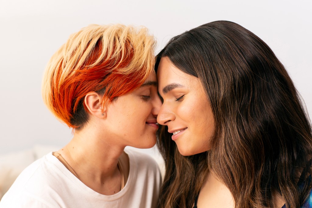 A transmasculine gender-nonconforming person and transfeminine non-binary person nuzzling