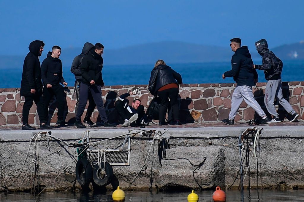 A journalist receives help from a woman as he is attacked by residents who are trying to prevent migrants from disembarking on the Greek island of Lesbos, on March 1, 2020.