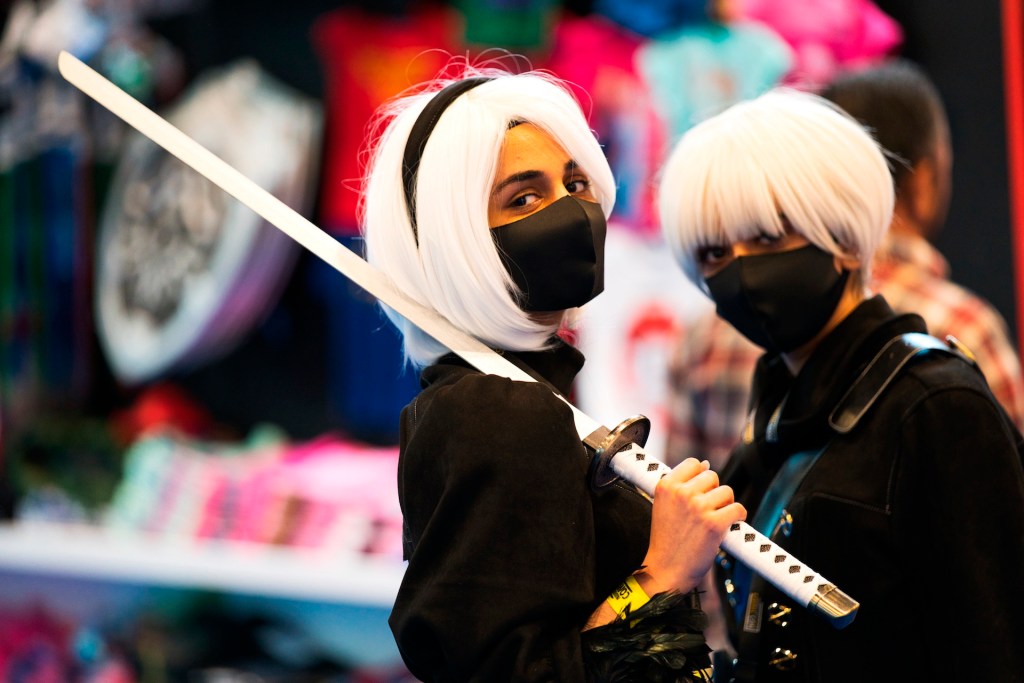 Two women wearing masks dressed as sword-wielding anime characters pose for a photograph at the Middle East Film & Comic Con in Dubai, United Arab Emirates, Thursday, March 5, 2020.