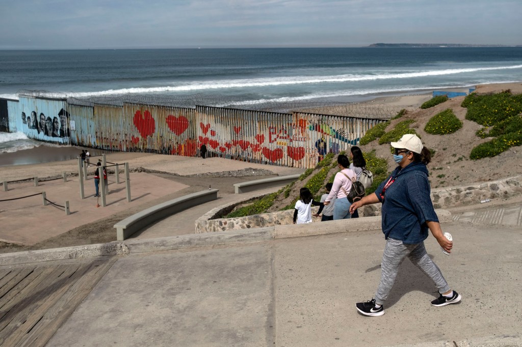 A woman wearing a protective mask walks near the US-Mexico border in Playas de Tijuana, Baja California state, Mexico, on February 28, 2020. (Photo by Guillermo Arias / AFP) (Photo by GUILLERMO ARIAS/AFP via Getty Images)