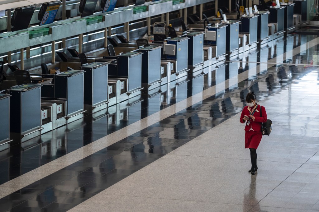 A flight attendant walking pass empty check-in counters at Hong Kong International Airport on February 22