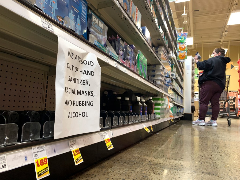 A shopper wearing a mask is pictured near a sign advising out-of-stock sanitizer, facial masks and rubbing alcohol at a store following warnings about COVID-19 in Kirkland, Washington on March 5, 2020. (Photo by JASON REDMOND/AFP via Getty Images)