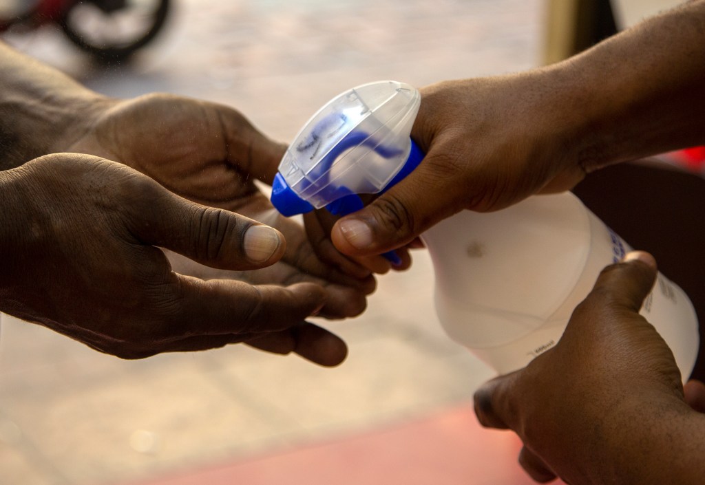 A security officer sprays a customer's hands with sanitizer inside a shop in downtown Johannesburg, South Africa, Friday, March 20, 2020. (AP Photo/Themba Hadebe)​