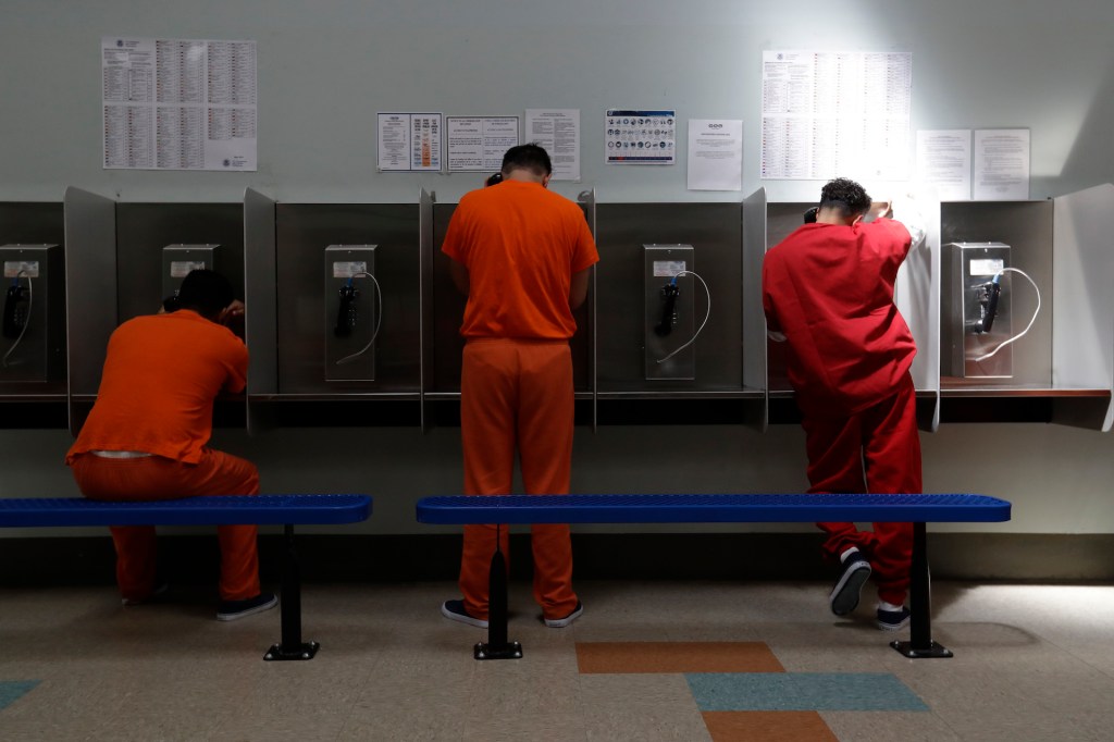 ICE detainees talk on telephones at the Adelanto ICE Processing Center in Adelanto, Calif.