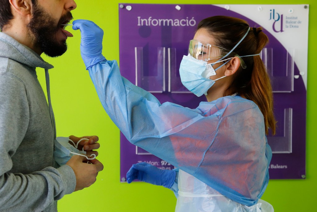 A health care worker takes a sample from a patient in the Balearic Island's Establiments district for a corona test.