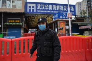 Petugas polisi berjaga-jaga di depan pasar ikan Huanan di Wuhan, tempat virus corona pertama kali terdeteksi. Hector Retamal / AFP