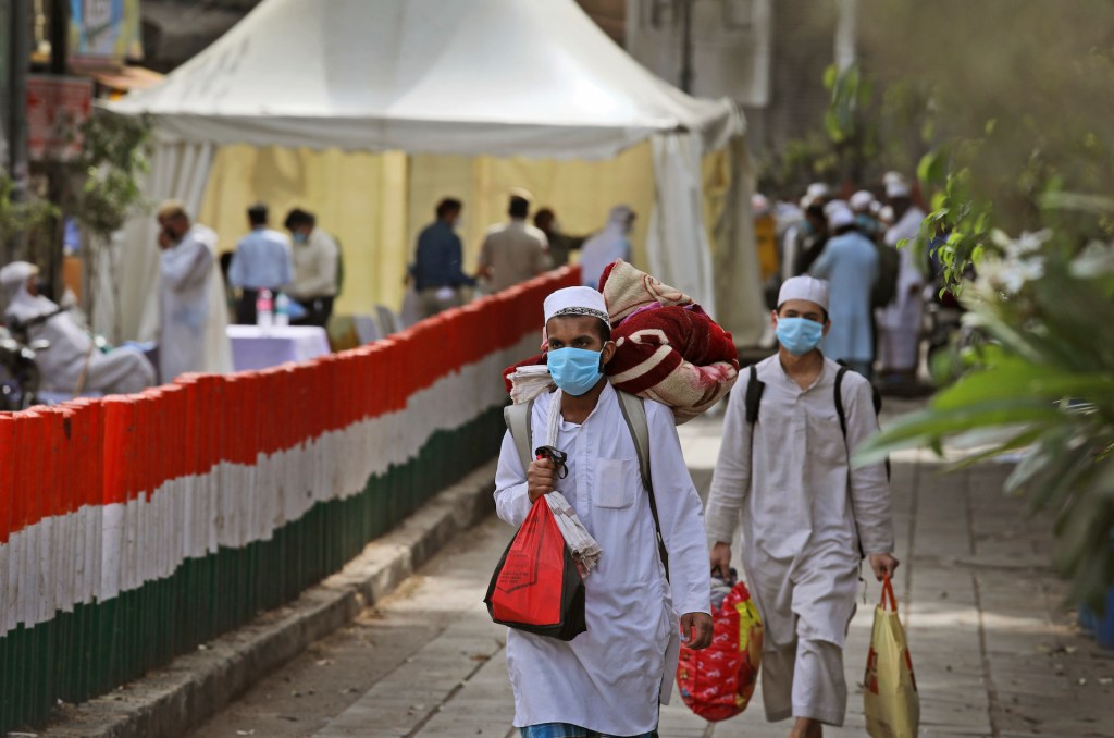 Muslim pilgrims walk towards a bus that will take them to a quarantine facility, amid concerns over the spread of the new coronavirus, at the Nizamuddin area of New Delhi, India, Tuesday, March 31, 2020.