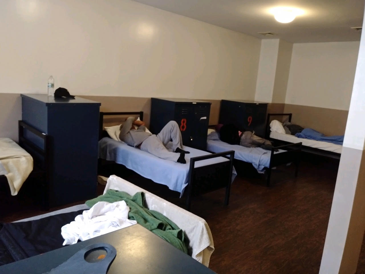 A photo of people lying on beds in a shelter.