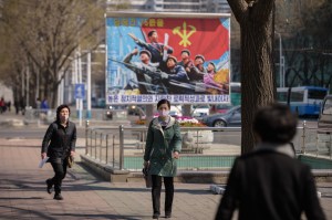 Dua orang maskeran berjalan di depan poster propaganda yang terpasang di jalanan Pyongyang pada 9 April 2020. Kim Won Jin / AFP