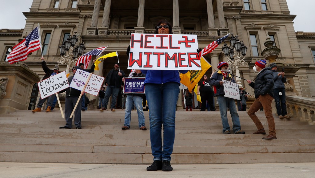 Dawn Perreca protests on the front steps of the Michigan State Capitol building in Lansing, Mich., Wednesday, April 15, 2020. (AP Photo/Paul Sancya)