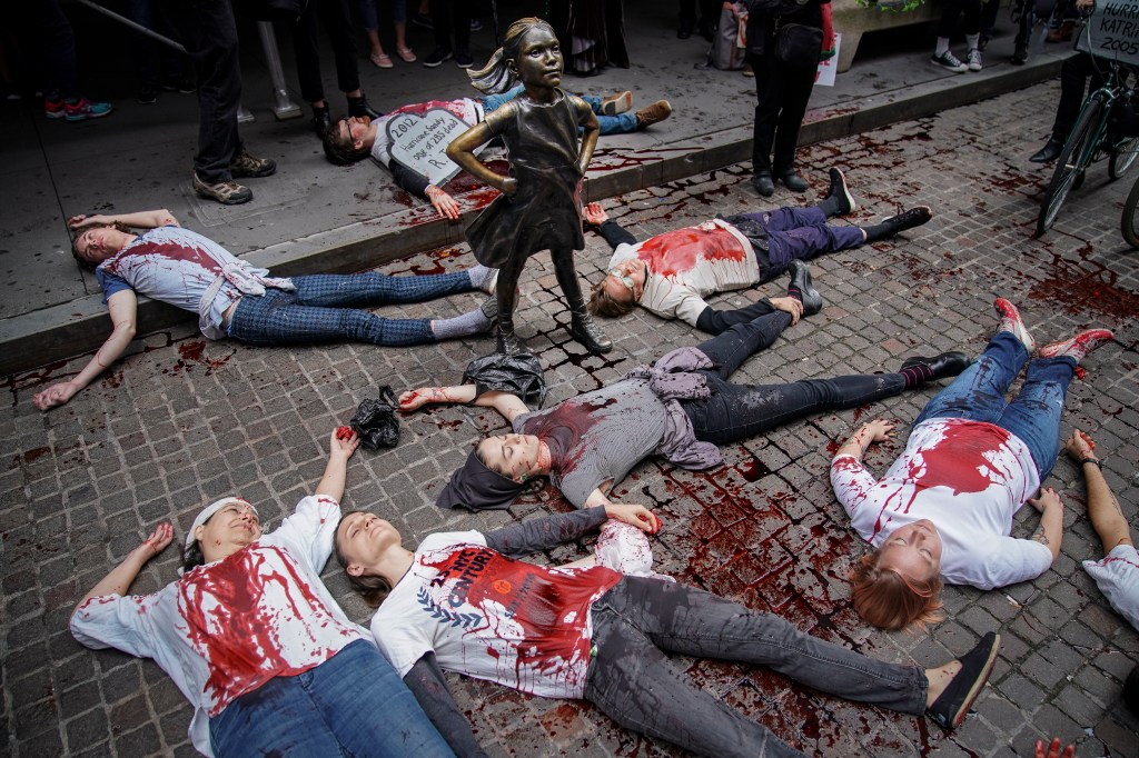 Protesters in fake blood lie on a street