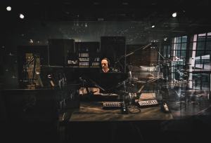 A DJ surrounded by equipment in a dark radio station.