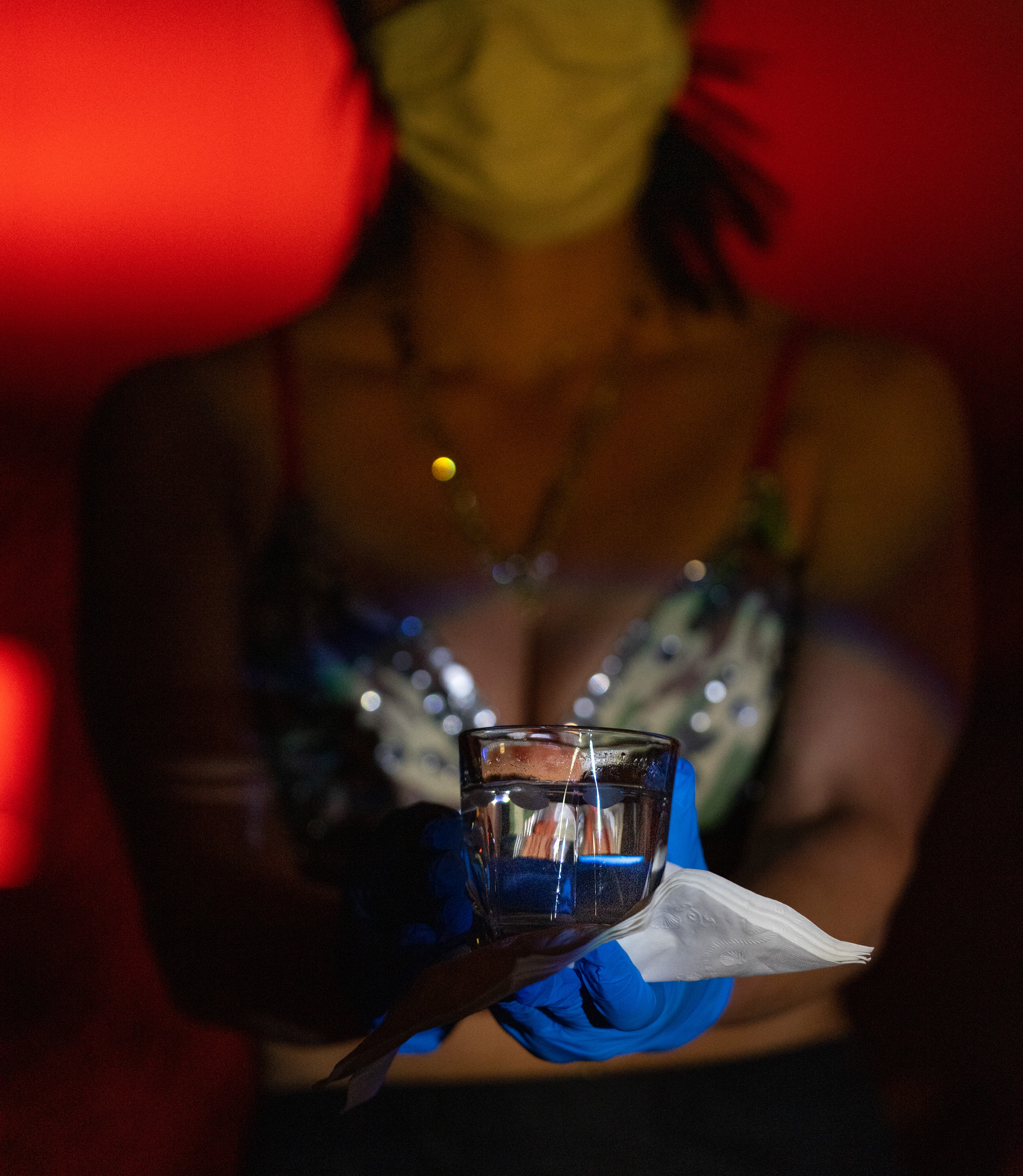 A waitress serves drinks wearing a mask and disposable gloves.