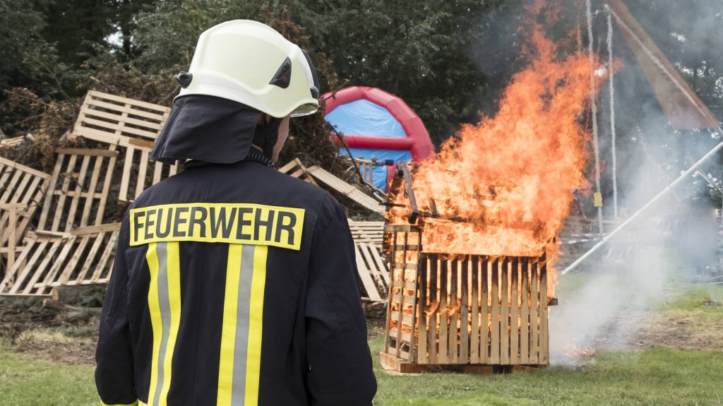 Feuerwehrfrau mit Feuer im Hintergrund