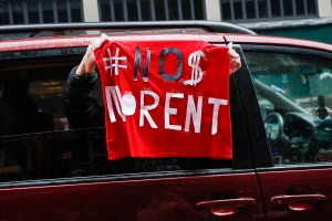 A sign with the message to cancel rent is displayed from a vehicle as a caravan of May Day protesters drives up 2nd Avenue outside the offices of New York Gov. Andrew Cuomo, Friday, May 1, 2020, in the Manhattan borough of New York. (AP Photo/John Minchil