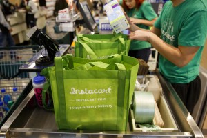 Instacart shoppers bag groceries. Many workers haven't received safety kits.