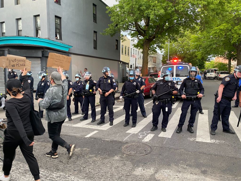 Protesters walking past a line of cops.