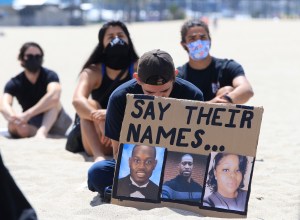 People sit during a moment of silence as they attend a Black Lives Matter protest in the Venice Beach area of Los Angeles Friday, June 12, 2020.