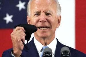 Democratic presidential candidate, former Vice President Joe Biden holds up a mask as he speaks during a campaign event June 30, 2020 at Alexis I. Dupont High School in Wilmington, Delaware.