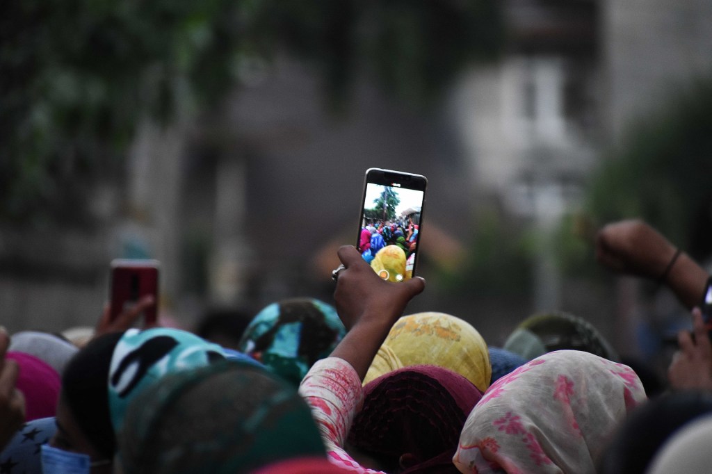 A woman shoots videos with a cellphone during a protest in Srinagar, Kashmir on June 21, 2020.